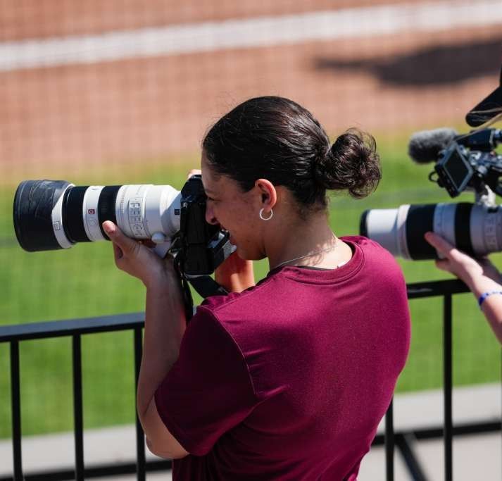 Photographer with a telephoto lens on the sidelines of a game