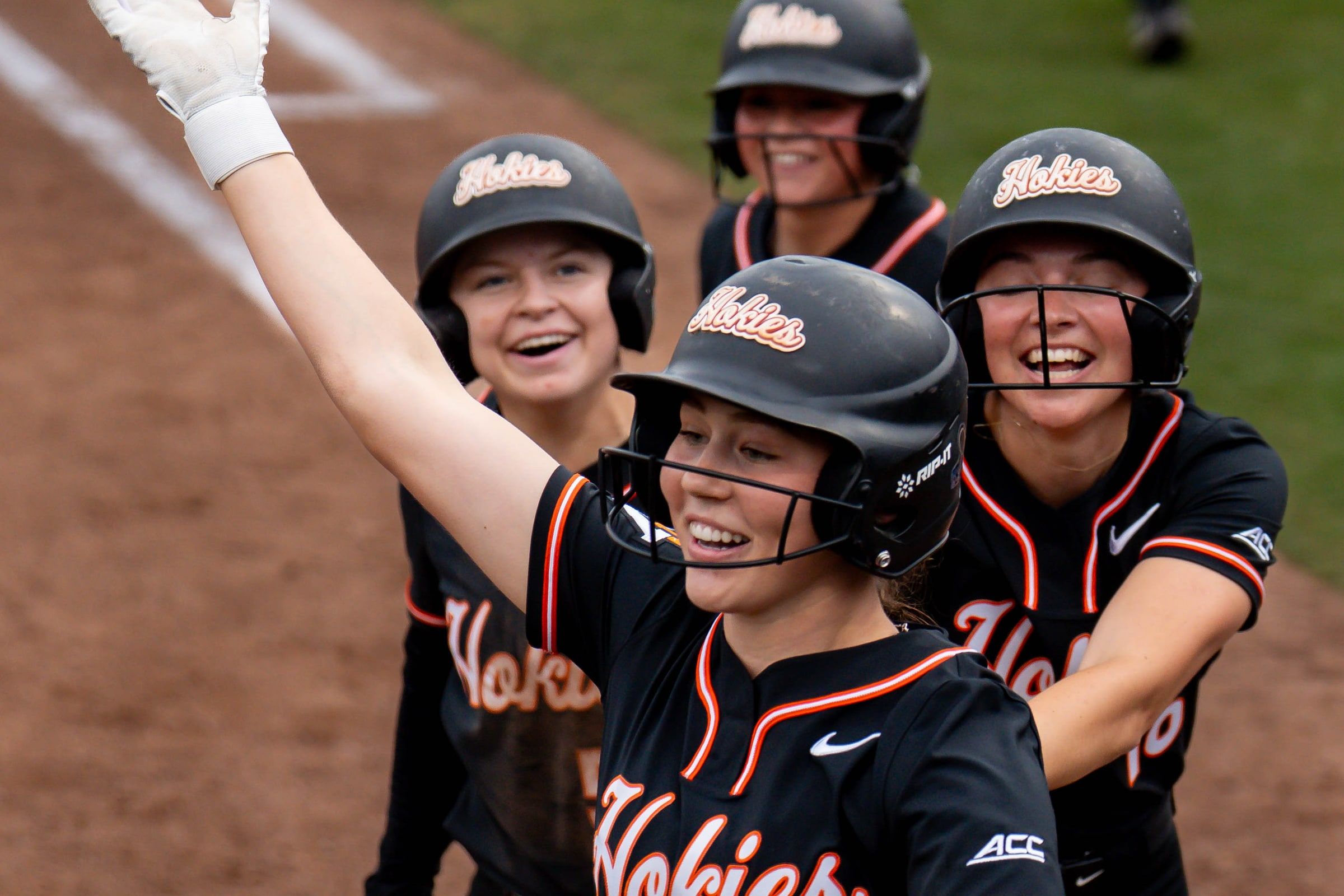 Softball players celebrating together, one with an arm raised