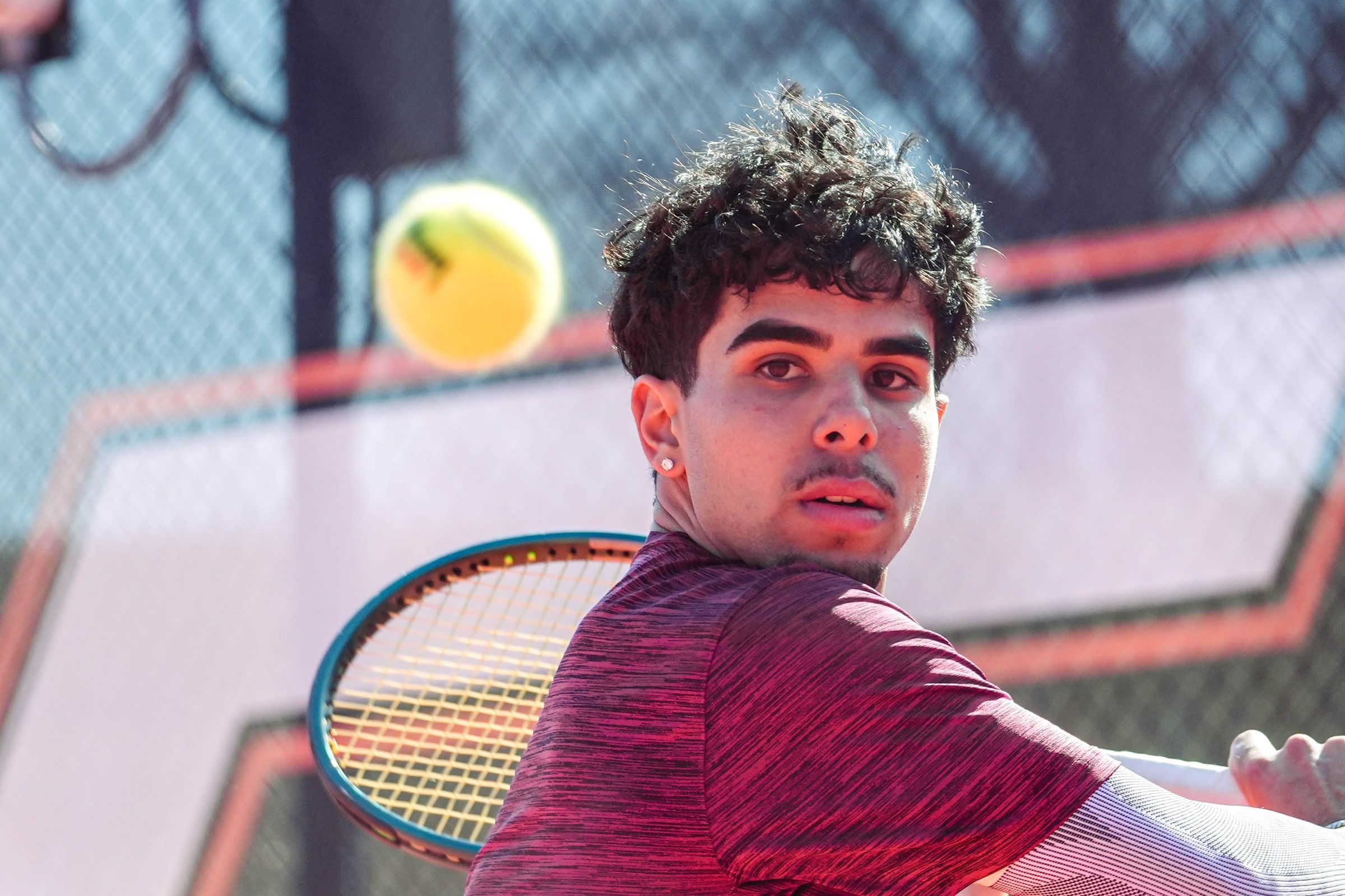 Tennis player hitting a forehand, with the ball in the air
